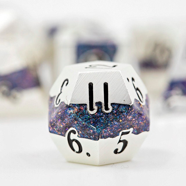 Closeup of a d12 with other metal polyhedral dnd dice in pearl silver metal with beautiful stripes of glittery blue and pink resin in the background.