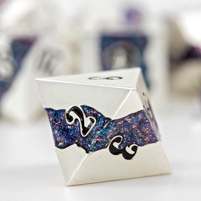 Closeup of a d8 with other metal polyhedral dnd dice in pearl silver metal with beautiful stripes of glittery blue and pink resin in the background.